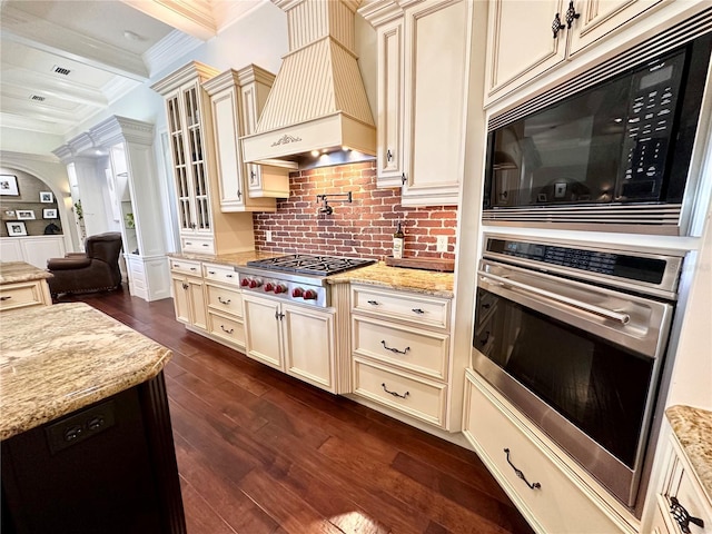 1570 Oakford Rd, Sarasota, FL 34240 - kitchen featuring cream cabinetry, appliances with stainless steel finishes, custom range hood, ornamental molding, and ornate columns