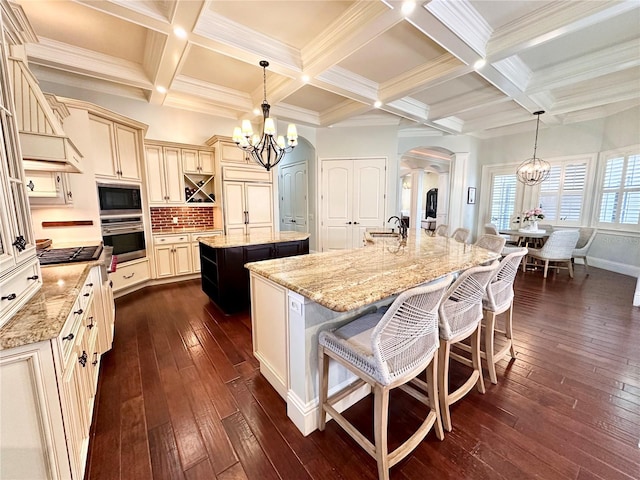 1570 Oakford Rd, Sarasota, FL 34240 - kitchen featuring a chandelier, a spacious island, cream cabinetry, arched walkways, and beam ceiling