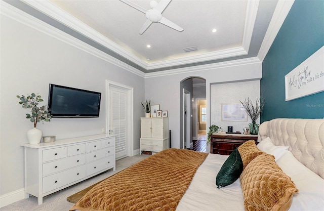 1570 Oakford Rd, Sarasota, FL 34240 - bedroom with arched walkways, a tray ceiling, ornamental molding, light carpet, and baseboards