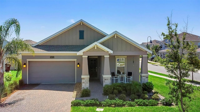 5052 Blanchard Ct, Saint Cloud, FL 34772 - view of front of home featuring a porch, an attached garage, a shingled roof, stone siding, and decorative driveway