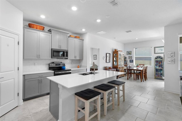 5052 Blanchard Ct, Saint Cloud, FL 34772 - kitchen with tasteful backsplash, gray cabinetry, a kitchen bar, appliances with stainless steel finishes, and a sink
