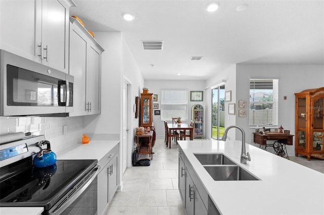 5052 Blanchard Ct, Saint Cloud, FL 34772 - kitchen with visible vents, a sink, decorative backsplash, light countertops, and stainless steel appliances