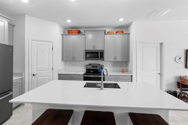 5052 Blanchard Ct, Saint Cloud, FL 34772 - kitchen with gray cabinetry, stainless steel appliances, light countertops, a kitchen bar, and backsplash