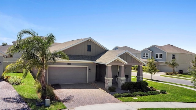 5052 Blanchard Ct, Saint Cloud, FL 34772 - view of front of house featuring a front yard, an attached garage, a shingled roof, decorative driveway, and board and batten siding