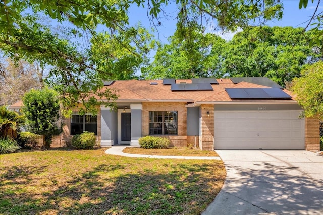 10400 Hunters Trail Ct, Orlando, FL 32817 - view of front of house featuring a front lawn, driveway, an attached garage, brick siding, and solar panels
