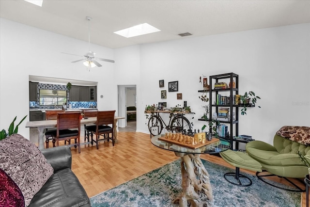 10400 Hunters Trail Ct, Orlando, FL 32817 - living room featuring light wood-type flooring, visible vents, ceiling fan, a skylight, and a towering ceiling