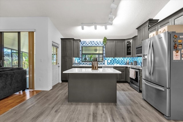 10400 Hunters Trail Ct, Orlando, FL 32817 - kitchen featuring a center island, light countertops, light wood-type flooring, decorative backsplash, and stainless steel appliances