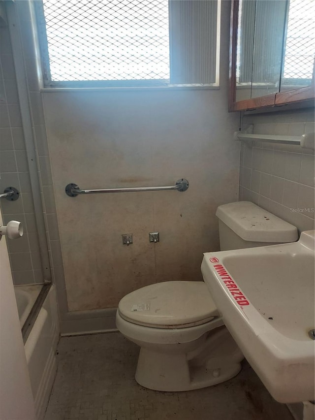 2155 Wood St Unit B4, Sarasota, FL 34237 - bathroom featuring plenty of natural light, toilet, tile walls, a sink, and washtub / shower combination