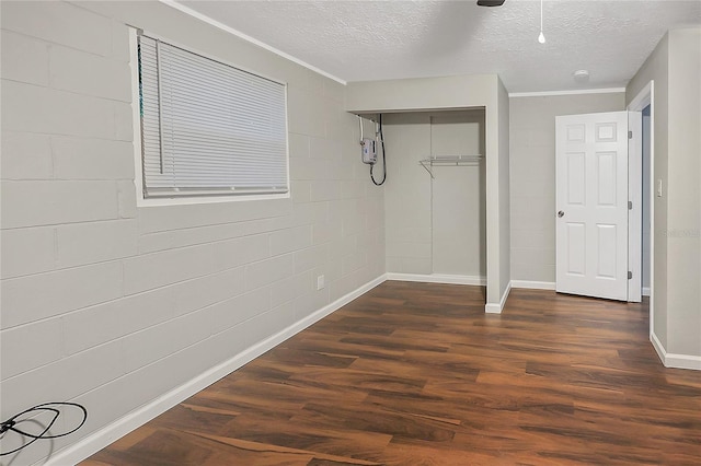 626 Marvin C Zanders Ave, Apopka, FL 32703 - unfurnished bedroom with concrete block wall, baseboards, dark wood finished floors, a closet, and a textured ceiling