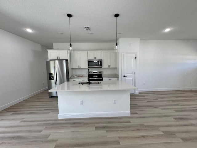 kitchen with visible vents, appliances with stainless steel finishes, an island with sink, and light countertops