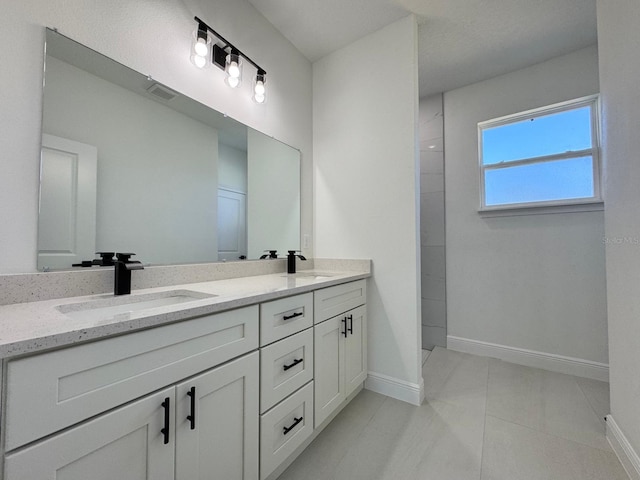 full bath featuring double vanity, baseboards, visible vents, and a sink