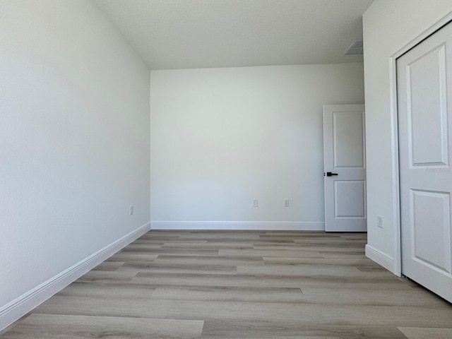 empty room featuring visible vents, light wood-style floors, and baseboards