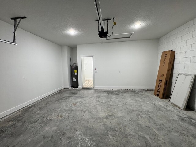 garage featuring concrete block wall, a garage door opener, baseboards, and electric water heater