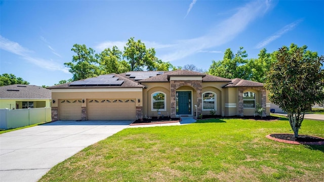view of front of home featuring driveway, fence, solar panels, a front lawn, and stucco siding