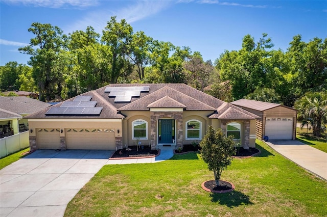 mediterranean / spanish home with an attached garage, stucco siding, solar panels, a front lawn, and driveway