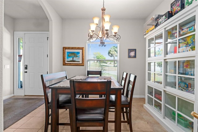 dining room featuring light tile patterned flooring, a notable chandelier, baseboards, and arched walkways