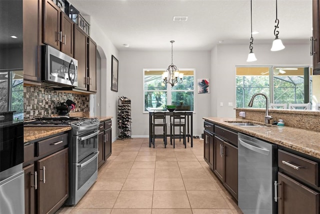 kitchen featuring visible vents, appliances with stainless steel finishes, dark brown cabinetry, backsplash, and light tile patterned floors