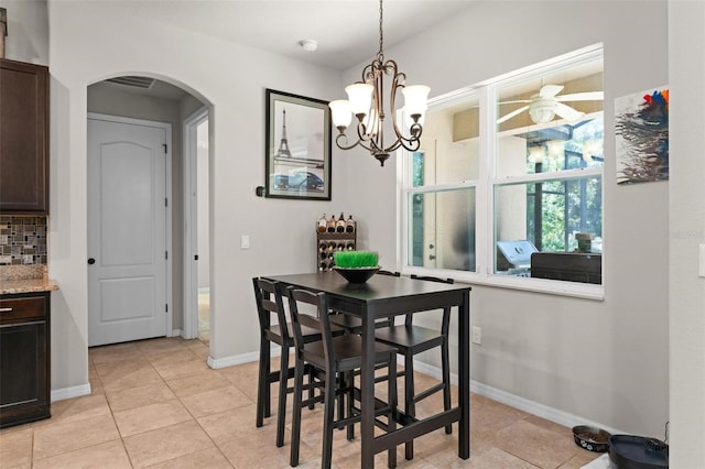 dining room featuring arched walkways, baseboards, light tile patterned floors, and ceiling fan with notable chandelier
