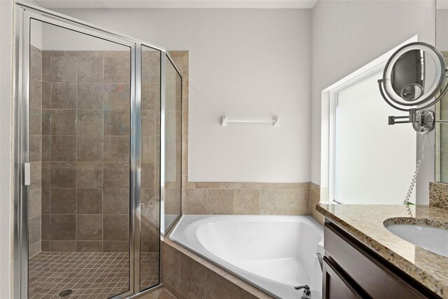 full bathroom featuring a shower stall, vanity, and a bath