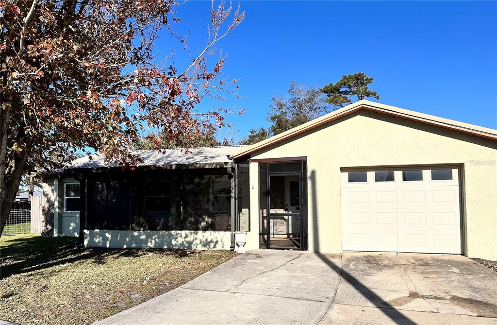 2209 Pike Ct, Cocoa, FL 32926 - ranch-style home with a garage, a sunroom, driveway, and stucco siding