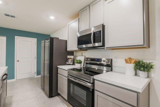 kitchen with light tile patterned floors, visible vents, stainless steel appliances, and light countertops