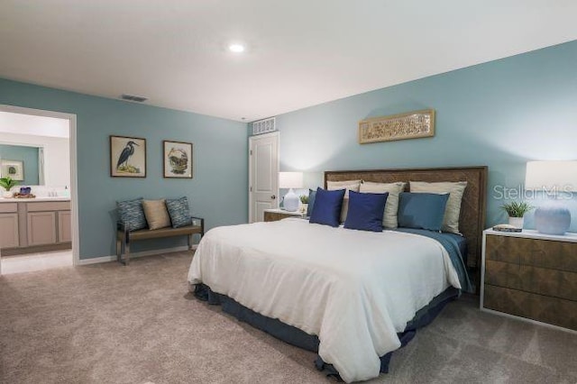 bedroom with light colored carpet, visible vents, and ensuite bathroom