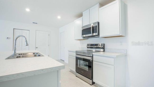 kitchen featuring light countertops, white cabinets, appliances with stainless steel finishes, and a sink