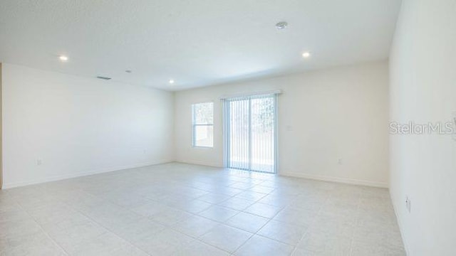 spare room with recessed lighting and baseboards