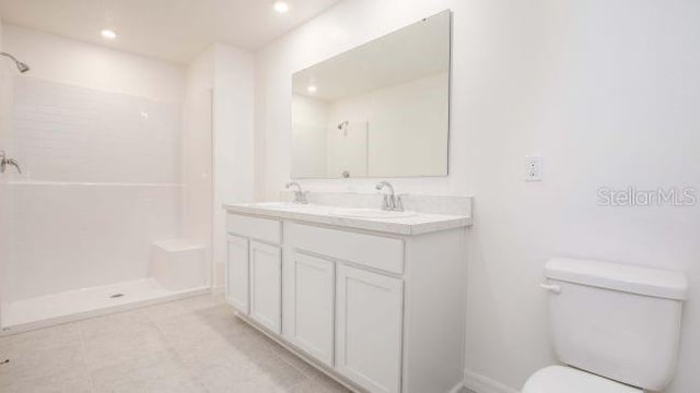 full bathroom featuring double vanity, toilet, walk in shower, and a sink