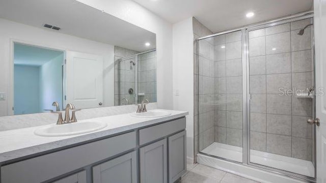 bathroom featuring double vanity, a stall shower, and a sink