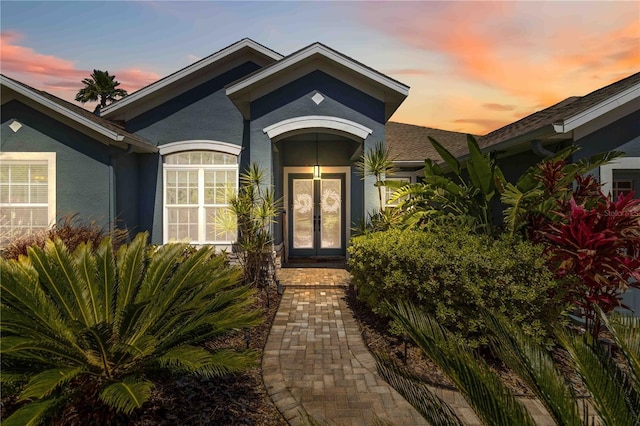 13136 Peregrin Cir, Bradenton, FL 34212 - exterior entry at dusk featuring french doors, stucco siding, and a shingled roof