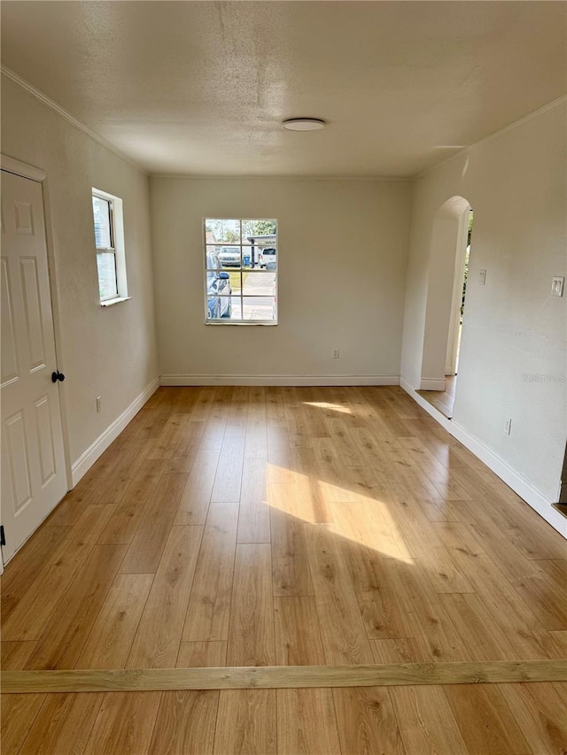 701 N 4th St, Haines City, FL 33844 - empty room with arched walkways, baseboards, a textured ceiling, and light wood-style flooring