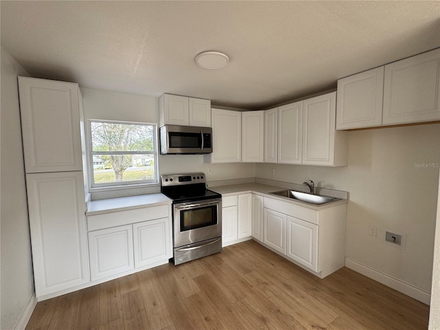 701 N 4th St, Haines City, FL 33844 - kitchen with a sink, white cabinetry, appliances with stainless steel finishes, light wood-type flooring, and baseboards