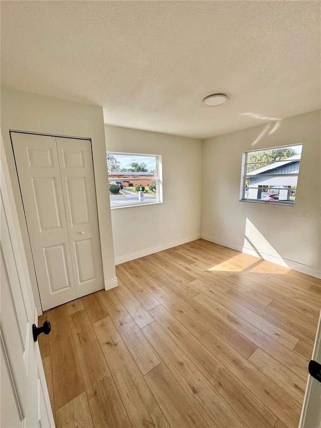 701 N 4th St, Haines City, FL 33844 - empty room featuring baseboards, light wood-style flooring, and a textured ceiling