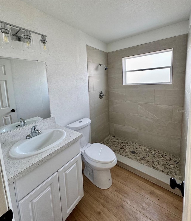 701 N 4th St, Haines City, FL 33844 - bathroom featuring toilet, tiled shower, vanity, wood finished floors, and a textured ceiling