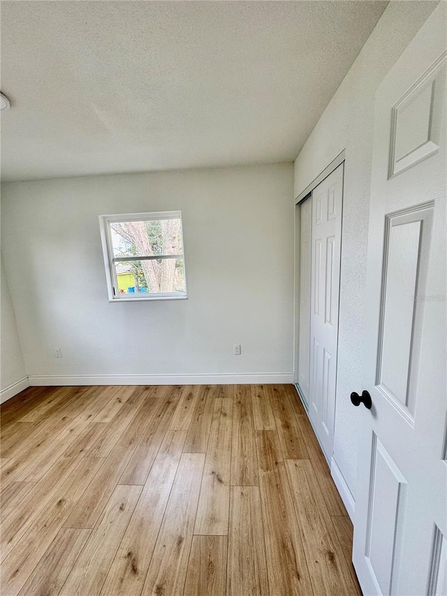 701 N 4th St, Haines City, FL 33844 - unfurnished bedroom with baseboards, a textured ceiling, a closet, and wood finished floors