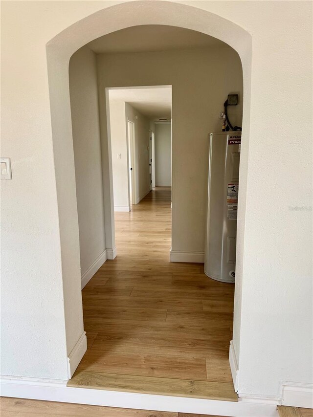 701 N 4th St, Haines City, FL 33844 - hallway with arched walkways, electric water heater, light wood-style floors, and baseboards