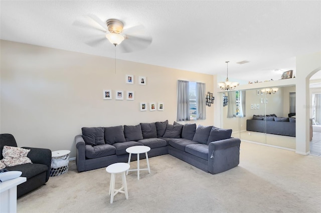 living room with ceiling fan with notable chandelier, visible vents, and light carpet