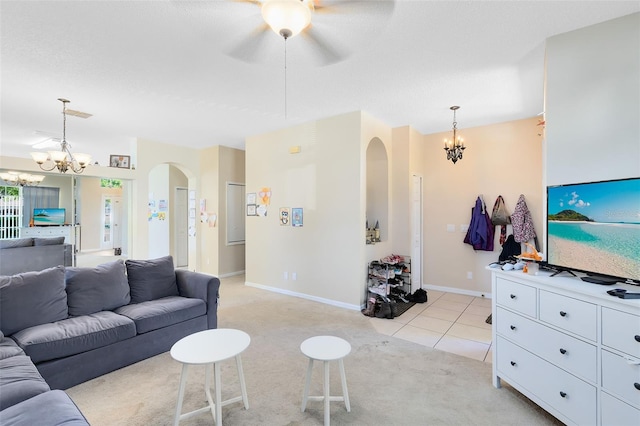 living room featuring visible vents, ceiling fan with notable chandelier, arched walkways, light tile patterned flooring, and light colored carpet