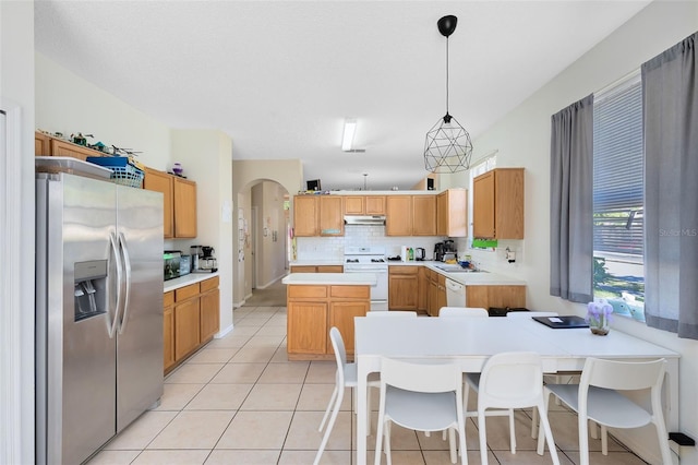 kitchen featuring stainless steel refrigerator with ice dispenser, under cabinet range hood, gas range gas stove, tasteful backsplash, and light tile patterned floors