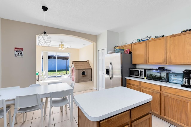kitchen featuring pendant lighting, a ceiling fan, a textured ceiling, stainless steel appliances, and light countertops