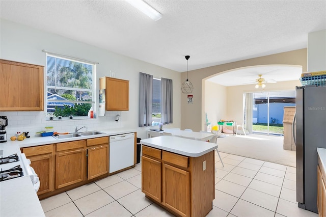kitchen with arched walkways, freestanding refrigerator, a sink, dishwasher, and range