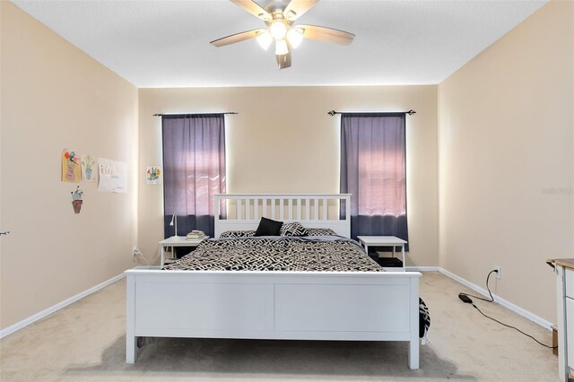 bedroom featuring light colored carpet, baseboards, and ceiling fan
