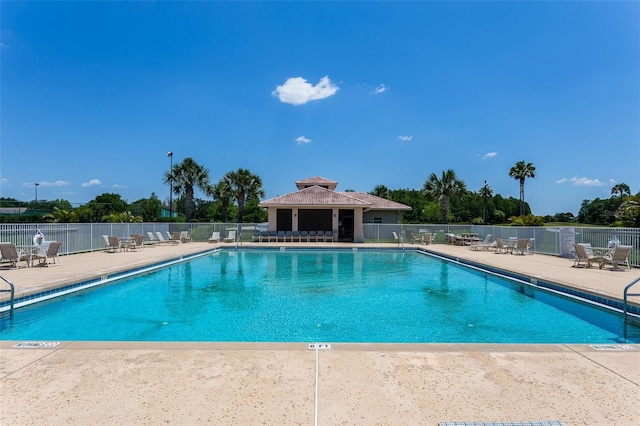 pool with a patio area and fence