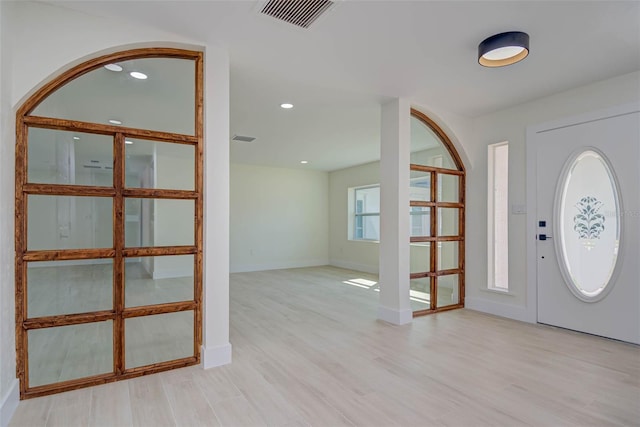 foyer entrance featuring light wood-style floors, visible vents, and baseboards