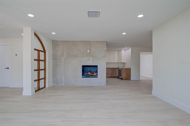 unfurnished living room with recessed lighting, a tile fireplace, visible vents, and baseboards