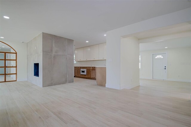 unfurnished living room with light wood-type flooring, a fireplace, baseboards, and recessed lighting