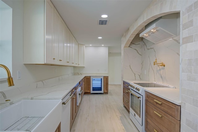 kitchen with wall chimney exhaust hood, wine cooler, a sink, visible vents, and white appliances
