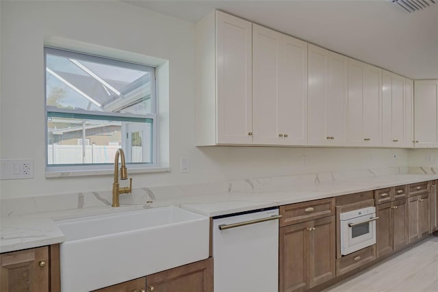 kitchen with visible vents, a wealth of natural light, white appliances, and a sink