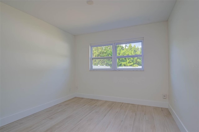 spare room featuring light wood finished floors and baseboards